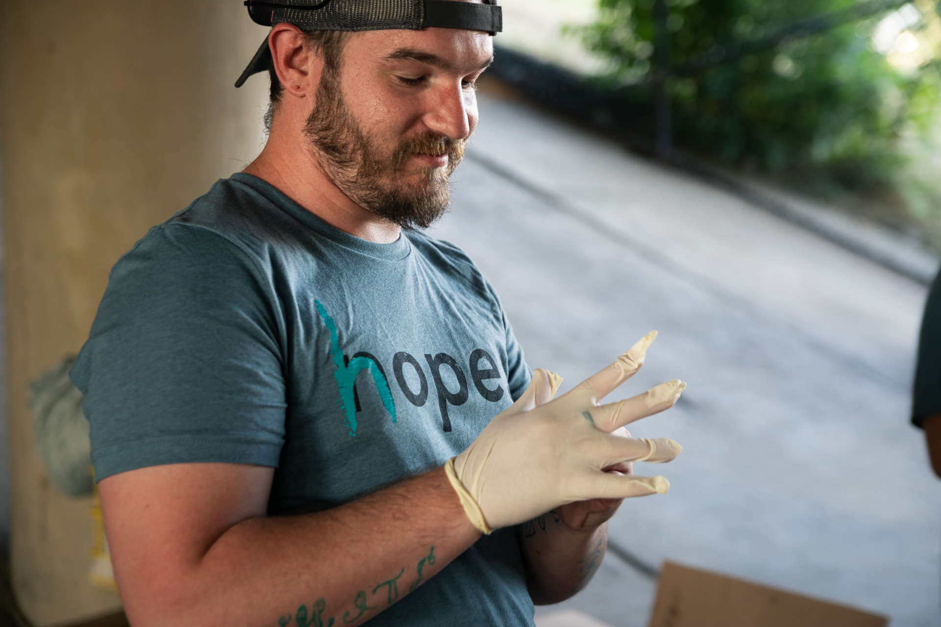 A member of the Sanga community putting on rubber gloves while volunteering at a community event.